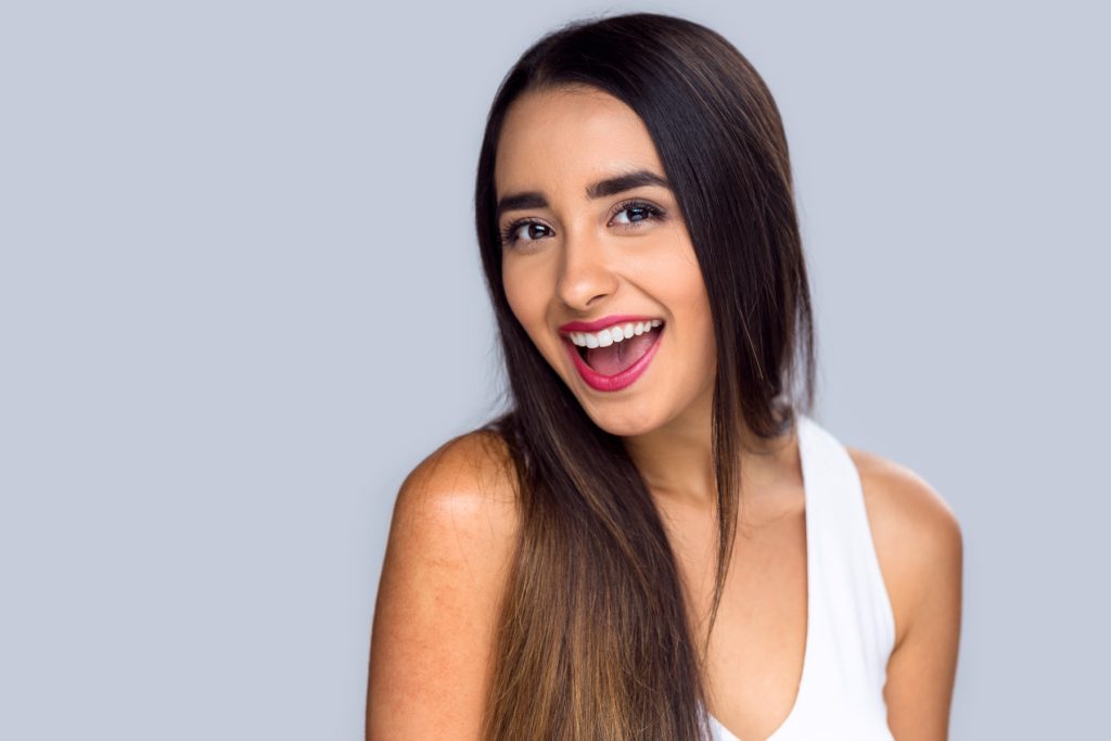 Beautiful hispanic girl proud and confident about her perfect white teeth smile